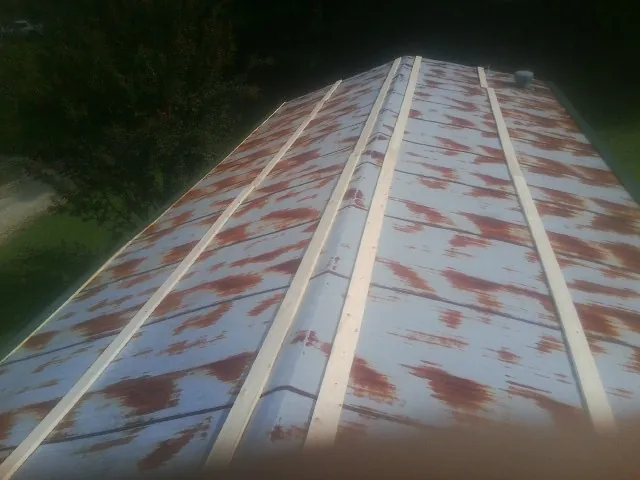 Rusted metal roof panels with new wood purlins before replacement in Kettle Falls