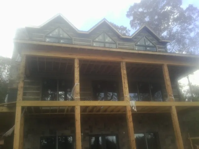 Dormers and porch framing on a large log home under construction — Roof Coating work by our crew in Kettle Falls