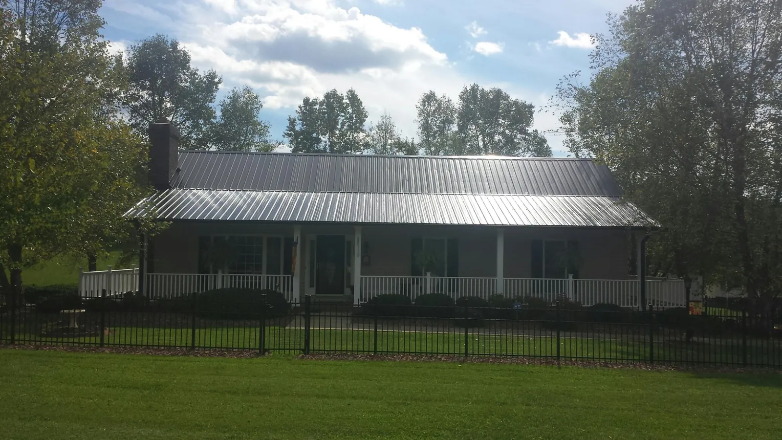 Gray metal roof on a brick ranch with a full width front porch — Gutter Guard Installation work by our crew in Kettle Falls