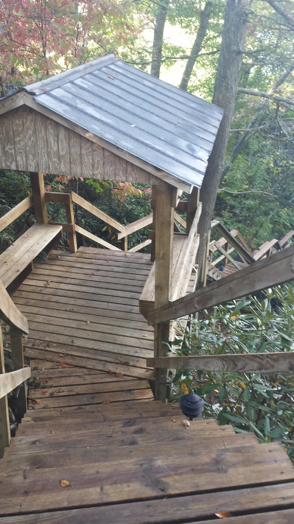 Metal roofed shelter over wooden steps on a wooded walkway — Skylight Repair & Installation work by our crew in Kettle Falls