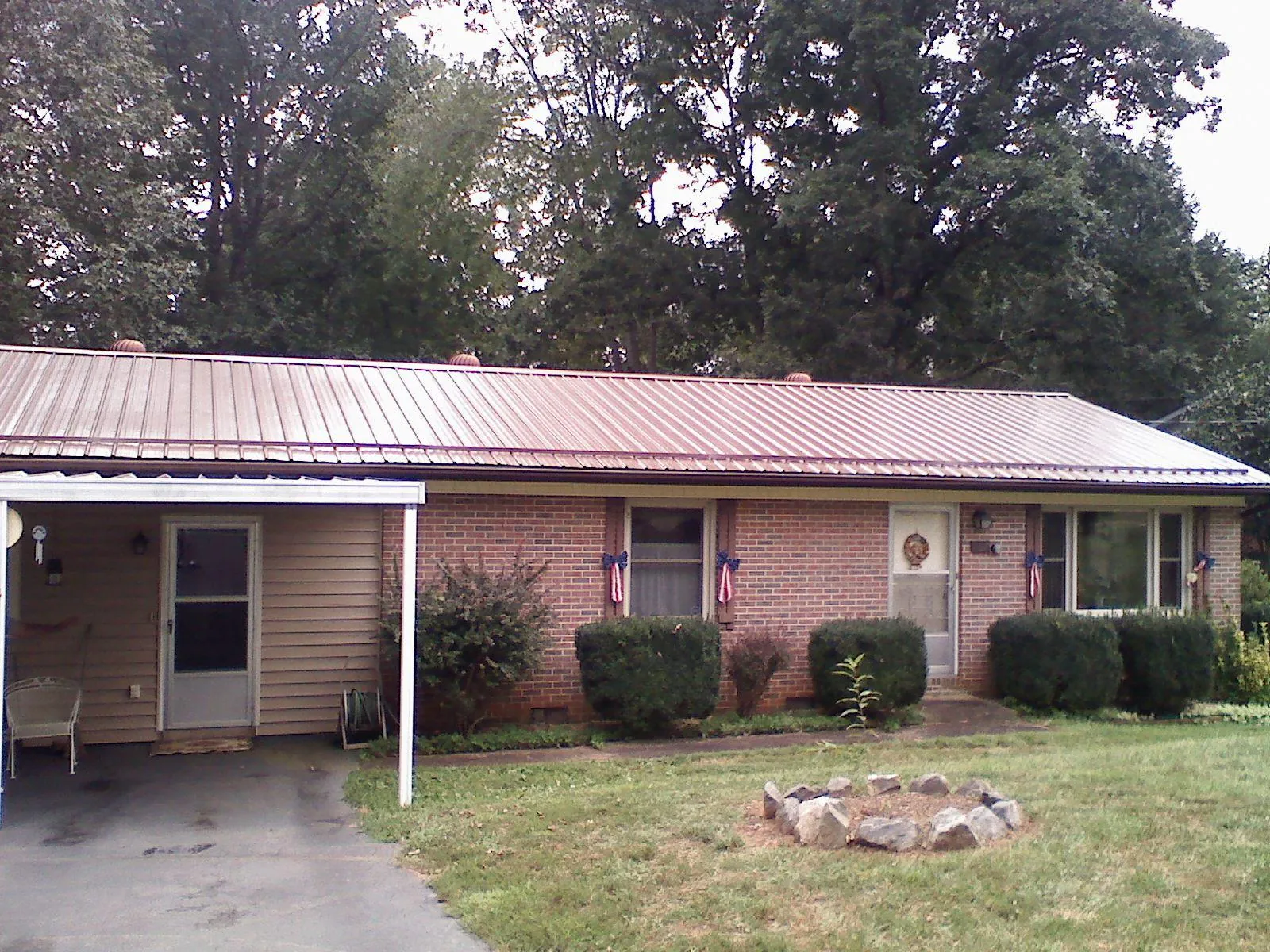 Bronze metal roof and carport on a brick ranch home — Roof Repair work by our crew in Kettle Falls