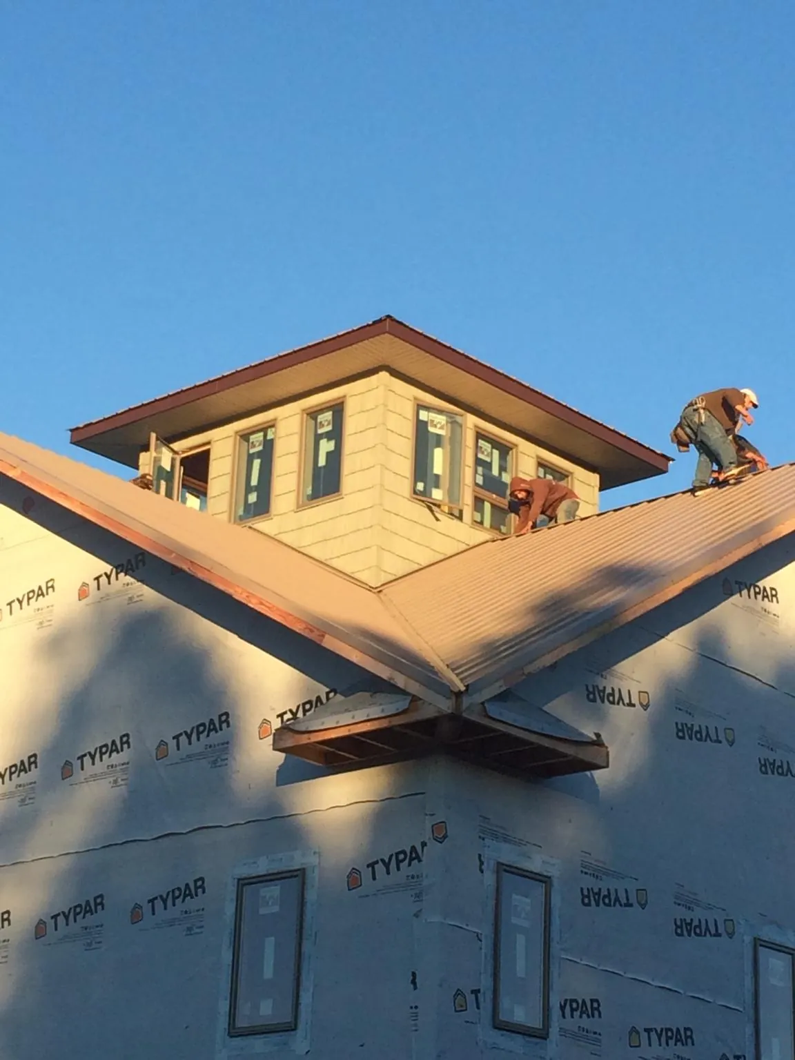 Roofers working around a rooftop cupola on a new metal roof at sunset — Roof Waterproofing in Kettle Falls by Roofing Brothers